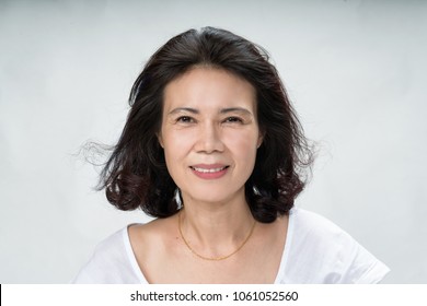 Portrait of beautiful mature asian woman with curly hair style smiling with joyful and charming on white background isolate. Close up happy and cheerful older lady wear white shirt health care concept