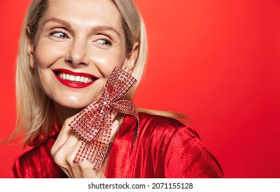 Portrait Of Beautiful Mature Woman Face With Few Wrinkles, Red Lips, Smiling Happy As Holding Christmas Gift Ribbon, Concept Of New Year Holidays Celebration, Studio Background