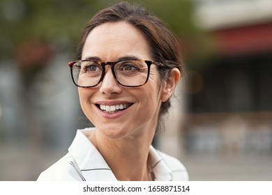 Portrait Of Beautiful Mature Woman Looking Away. Cheerful Woman Wearing Eyeglasses And Smiling. Close Up Face Of Happy Carefree Lady Wearing Eyeglasses On City Street.