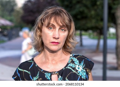 portrait of a beautiful mature woman of middle age 50 years old with blond hair with a pensive look, in the park