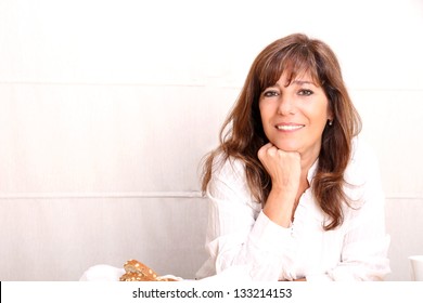 Portrait Of A Beautiful Mature Woman Sitting In The Kitchen.