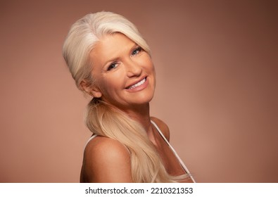 Portrait of a beautiful mature woman with beautiful skin, standing over a beige background  - Shutterstock ID 2210321353