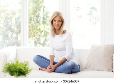 Portrait Of Beautiful Mature Woman Smiling While Sitting At Sofa At Home. 