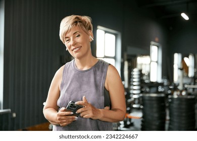 Portrait of beautiful mature woman in sportswear visiting stylish gym. Following sportive life and training regularly. Concept of active, sportive and healthy lifestyle, fitness, body care, ad