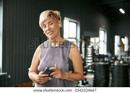 Portrait of beautiful mature woman in sportswear visiting stylish gym. Following sportive life and training regularly. Concept of active, sportive and healthy lifestyle, fitness, body care, ad