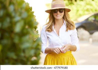 Portrait Of Beautiful Mature Woman Walking On The Street. Happy Female Wearing Straw Hat And Sunglasses While On Summer Vacation.