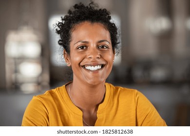 Portrait of a beautiful mid adult woman smiling at home. Middle aged african woman in casual looking at camera with copy space. Cheerful mixed race girl relaxing at home with big laugh.