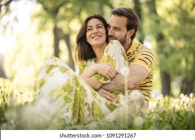 Portrait Of Beautiful Middle Age Couple Sitting At Nature. 