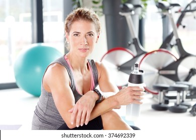 Portrait Of Beautiful Middle Age Woman Taking A Break From Her Fitness Workout And Drinking Protein Shake. 