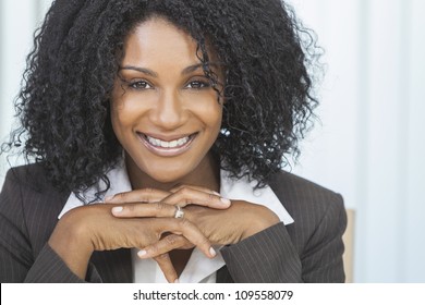 Portrait Of A Beautiful Middle Aged African American Woman Or Businesswoman Sitting Relaxing & Smiling