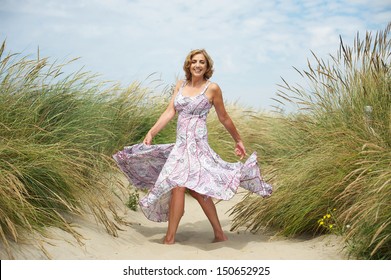 Portrait Of A Beautiful Middle Aged Woman Dancing In The Sand At The Beach