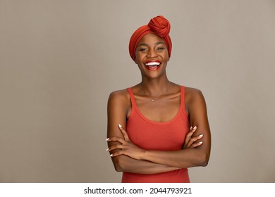 Portrait of beautiful middle aged woman with crossed arms and red headband smiling against brown wall. Cheerful woman wearing ethnic headscarf with folded arms while looking at camera.  - Powered by Shutterstock