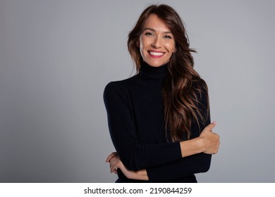 Portrait of beautiful middle aged woman with brunette hair. Confident female wearing black turtleneck sweater while posing at dark background. Copy space. 