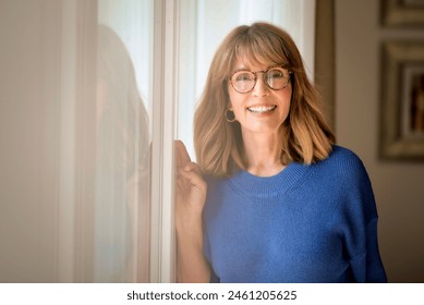 Portrait of a beautiful middle-aged woman looking a camera and smiling. Blond haired female wearing blue shirt and eyewear. Copy space. - Powered by Shutterstock