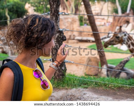 Portrait of a beautiful model and tourist with the backdrop of the Giraffes of the Valencia Bioparc. Rothschild's giraffe (Giraffa camelopardalis rothschildi) is a subspecies of the giraffe.