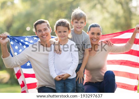 portrait of beautiful modern american family with USA flag outdoors