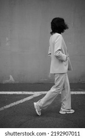 Portrait Of Beautiful Modern Woman In Parking Area. Fashionable. White Suit. Crop Top. Black Hair. Slim And Tall. Daily Life. Work And Leisure. City Background. Black And White Photo