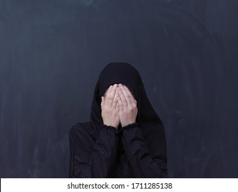 portrait of beautiful muslim woman in fashionable dress with hijab making traditional prayer to God, keeps hands in praying gesture isolated on black chalkboard background representing modern islam  - Shutterstock ID 1711285138
