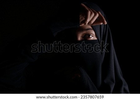 Portrait of Beautiful Muslim Woman in niqab on black background	                               
