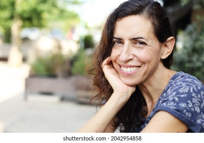 Portrait of beautiful natural 50 years old woman sitting in street cafe  