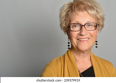 portrait of a beautiful old woman with beautiful smile, sparkling eyes, 70, wearing glasses and a yellow cardigan