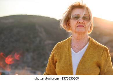 Portrait Of Beautiful Old Year Woman Looking To The Aunset. Wearing White T-shirt And Yellow  Cardigan