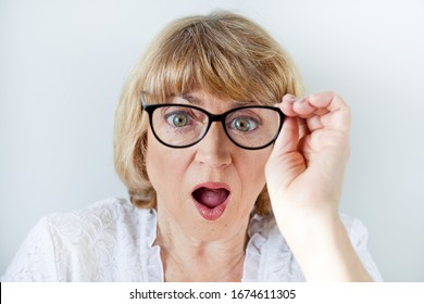 Portrait of a beautiful older blonde woman in glasses with big eyes, surprise opening her mouth, discounts or discount. on white background