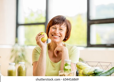 Portrait Of A Beautiful Older Woman With Green Healthy Food On The Table Indoors On The Window Background