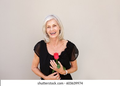 Portrait Of Beautiful Older Woman Laughing With Red Rose In Black Blouse