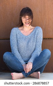 Portrait Of A Beautiful Older Woman Sitting And Smiling With Wind Blowing Hair