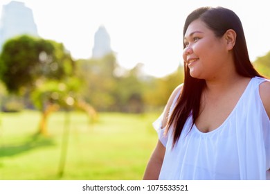 Portrait of beautiful overweight Asian woman relaxing at the park in the city of Bangkok, Thailand