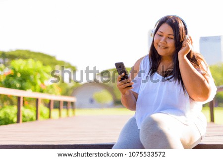 Portrait of beautiful overweight Asian woman relaxing at the park in the city of Bangkok, Thailand