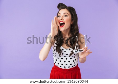 Portrait of a beautiful pin-up girl wearing bright makeup standing isolated over violet background, screaming loud