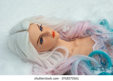 Portrait Of A Beautiful Realistic Doll Girl Lies On The Snow