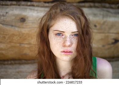 Portrait of the beautiful red haired girl and wood wall