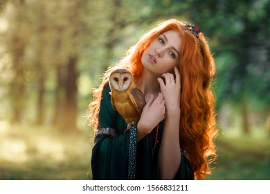 Portrait of beautiful redhead girl in green dress with owl on her hand