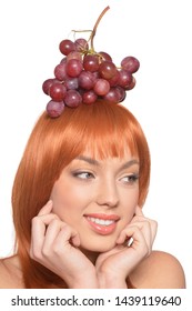 Portrait of beautiful redhead young woman with red grapes on head