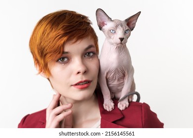 Portrait Of Beautiful Redhead Young Woman With Short Hair, Dressed In Red Jacket And Playful Cat Sitting On Her Shoulder. Hipster Woman Looking At Camera. Studio Shot On White Background. Part Series.