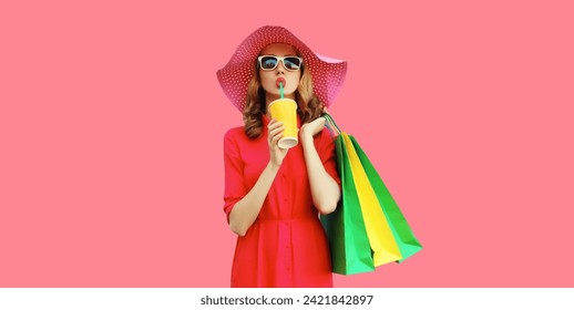 Portrait of beautiful relaxed young woman model with colorful shopping bags drinking juice in summer straw hat, dress on pink studio background - Powered by Shutterstock