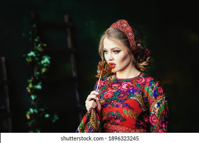 Portrait Of A Beautiful Russian Girl In A Kokoshnik And Traditional Dress. She Is Holding A Cockerel (lollipop) On A Stick. Russian Folk, Retro, Ethno. Pavlovo Posad Shawl. Selective Focus Photo