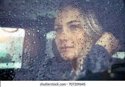 Portrait Of A Beautiful Sad Woman Sitting In The Car In Rainy Weather, Pensive Girl Looking Through The Window Glass With Rain Drops, Autumn Melancholy Concept