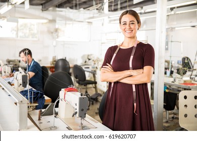 Portrait of a beautiful seamstress carrying a tape measure and working in a textile factory - Powered by Shutterstock