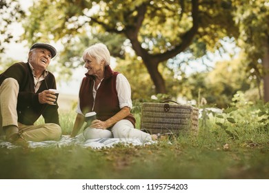 Portrait of beautiful senior couple sitting on blanket outdoor enjoying time together. Old couple picnicking on weekend holiday. - Powered by Shutterstock