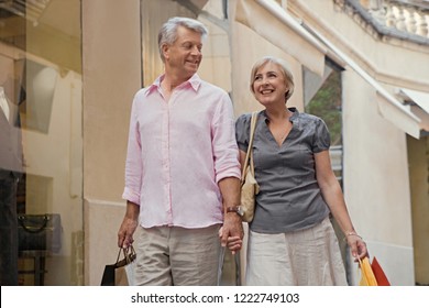 Portrait Of Beautiful Senior Couple Walking In Shopping Street Carrying Bags, Vacation Trip Outdoors. Mature Consumer People In Expensive City Break Travel, Leisure Recreation Lifestyle.