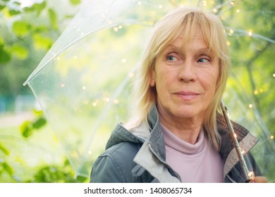 Portrait Of Beautiful Senior Woman With Transparent Umbrella With Light Bokeh Background