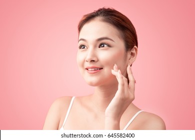 Portrait of Beautiful Skin care woman enjoy and relax touching her face on pink background