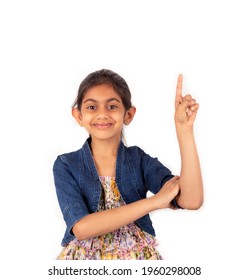 Portrait of a beautiful and smart Indian girl showing and pointing up  with index finger while smiling confident and happy. Marketing and advertising concept.