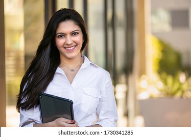 Portrait Of A Beautiful Smiling Cheerful Female Indian American Successful Business Woman CEO Entrepreneur At The Workplace, Standing Confidently