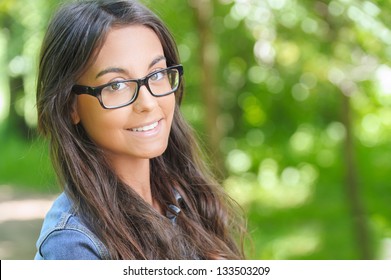 Portrait Of Beautiful Smiling Dark-haired Young Woman, Against Summer Green Park.