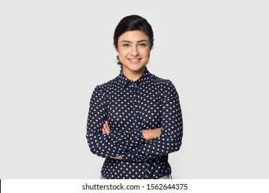 Portrait beautiful smiling Indian girl with arms crossed standing isolated on grey studio background, pretty young woman with healthy toothy smile looking at camera, satisfied client customer